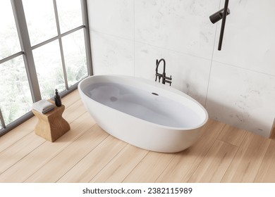 Vista superior del moderno interior del cuarto de baño con paredes de mármol blanco, suelo de madera y cómoda bañera blanca junto a una ventana con vistas tropicales. 3.ª representación