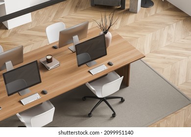 Top view on bright office room interior with four desktops and armchairs, shelves, plant, lamp, books and oak wooden parquet floor. Perfect place for working process. 3d rendering