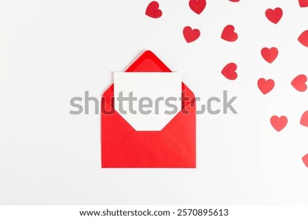 Top view of red envelope, white card on white background. Valentine's day, red hearts, love. Post flat lay, copy space.