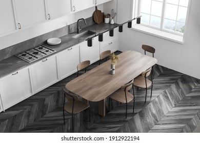 Top View Of White Kitchen Room With Wooden Eating Table And Chairs. White Kitchen Set And Window, Black Parquet Floor, 3D Rendering No People