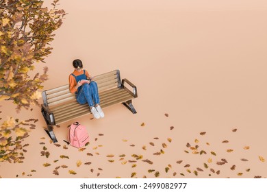 Top view of a woman wearing glasses and casual clothing sitting on a park bench reading a book, next to an autumn tree with falling leaves. Concept of relaxation, study and autumn season. 3d rendering - Powered by Shutterstock