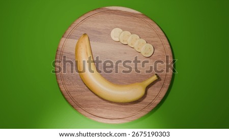 A top-down view 3D render of a banana half with slices arranged on a round wooden cutting board against a green studio backdrop. The minimal composition emphasizes freshness and design.