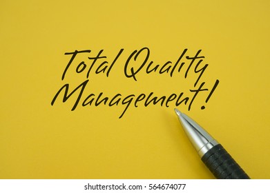 Total Quality Management! note with pen on yellow background