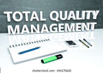 Total Quality Management - text concept with chalkboard, notebook, pens and mobile phone. 3D render illustration.