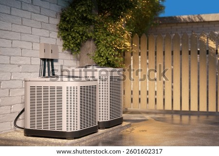 Two air conditioning units installed outside a house, placed on a concrete platform against a brick wall, with electrical wiring and a wooden fence in the background. 3d image