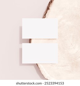 Two blank business cards placed on a tree stump surface, perfect for eco-friendly branding, nature-inspired stationery mockups, or rustic business presentations. - Powered by Shutterstock