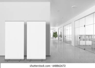 Two blank roll up banner stands in bright office interior with clipping path around ad stand. 3d illustration