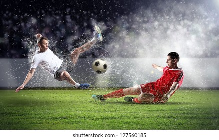 two football players in jump to strike the ball at the stadium - Powered by Shutterstock