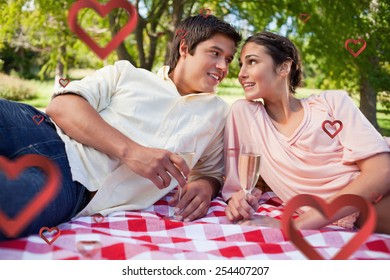 Two friends looking at each other while having a picnic against hearts - Powered by Shutterstock