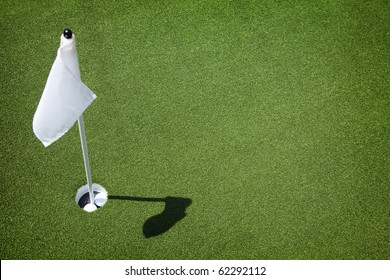 Two Golf Balls Sit Inside Cup On Golf Course Putting Green With Flag.