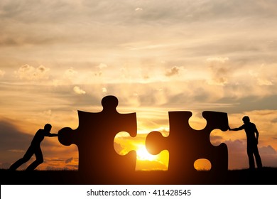 Two men connect two puzzle pieces. Sunset sky. Concept of business solution, teamwork, solving a problem, challenge - Powered by Shutterstock