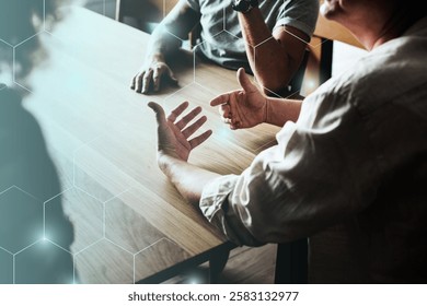 Two people discussing at a table, hands gesturing. Engaged in conversation, the discussion is animated. Hands emphasize the discussion's intensity. Business meeting conference