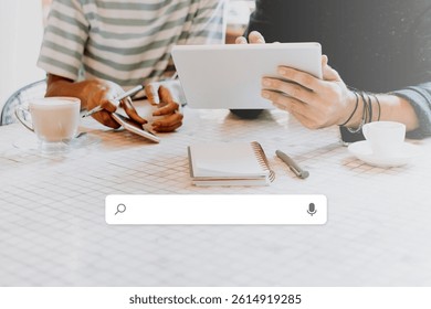 Two people using tablets at a cafe. Tablets on a cafe table. Casual cafe setting with tablets and coffee. Notepad and coffee cups on the table. Futuristic technology concept.