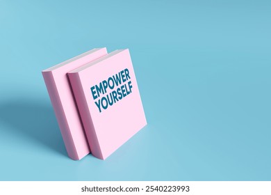 Two pink books with the text empower yourself on a light blue background promoting self-improvement and personal development. 3D render. - Powered by Shutterstock