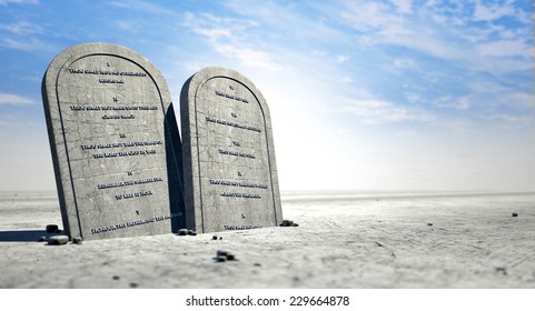 Two stone tablets with the ten commandments inscribed on them standing in brown desert sand in front of a blue sky