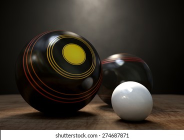 Two wooden lawn bowling balls surrounding a white jack on a wooden isolated dark studio background