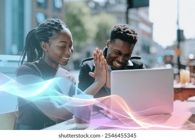 Two young African American adults, a man and a woman, smiling and high-fiving while working on a laptop outdoors. The African American pair are enjoying their teamwork. Business teamwork connection. - Powered by Shutterstock