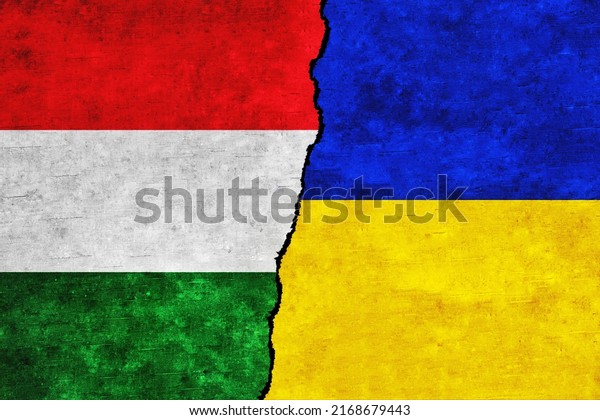 Ukraine and Hungary painted flags on a wall with\
a crack. Ukraine and Hungary relations. Hungary and Ukraine flags\
together