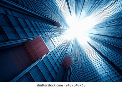 An upward view captures towering skyscrapers reaching toward a clear blue sky, their glass facades reflecting the bright sunlight in a magnificent urban display. - Powered by Shutterstock