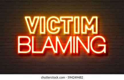 Victim Blaming Neon Sign On Brick Wall Background