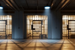 A View Through The Bars Of The Prisoner's Cell Doors, Reveals A Small Room With A Bed, Small Table, Chair, And Sink. The Position Of The Observer Is From The Corridor Outside The Cell. Hallway