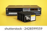 Vintage videocassette recorder and video cassettes isolated on yellow background. 3D illustration.