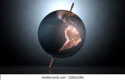 A vintage world globe tilted and standing on a central axis on an isolated spotlit dark background