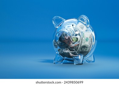 A vivid representation of savings and financial growth, this image showcases a clear piggy bank teeming with U.S. currency, set against a stark blue backdrop. - Powered by Shutterstock