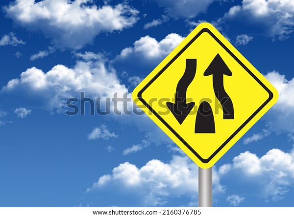Warning road sign TStart of Divide Highway. Clouds\
and yellow road\
signs.