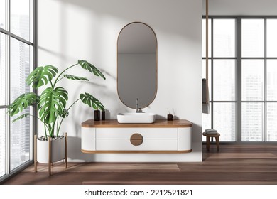 White Bathroom Interior With Sink And Oval Mirror, Stool With Towel And Big Plant On Hardwood Floor. Panoramic Window On City View. 3D Rendering