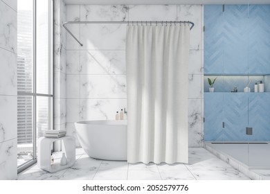 White and blue bathroom interior design, using a galss shower cabin, a niche shelf, a tub with a curtain, a side table and floor and wall tiles. A concept of a modern apartment.