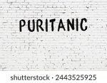 White brick wall with inscription puritanic handwritten with black paint