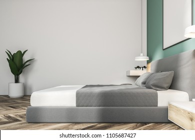 White and green bedroom interior with a wooden floor, a king size bed and a frame vertical poster hanging above it. 3d rendering mock up - Shutterstock ID 1105687427