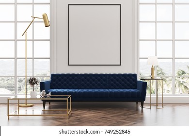 White living room interior with a wooden floor, loft windows, a blue sofa, a coffee table and a framed vertical poster on a white wall. 3d rendering mock up