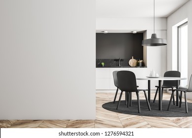 White round table with gray chairs standing in modern kitchen with white, black and black marble walls, wooden floor and white countertops. Mock up wall on the left. 3d rendering - Shutterstock ID 1276594321