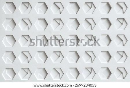 a white, textured surface featuring a grid of hexagonal indentations. Each hexagon has a three-dimensional, geometric design with internal triangular and rectangular patterns