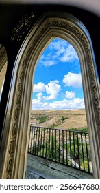 Window inside a castle in Spain overlooking a small village with a blue sky