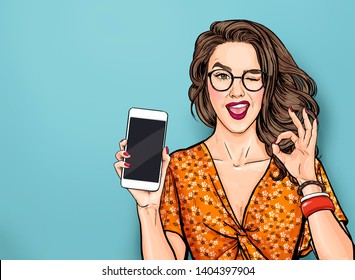 Winking woman in glasses showing smart pone and OK sign. Pop art girl holding phone. Digital advertisement female model showing the message or new app on cellphone.