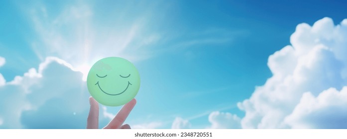 Woman holding smile icon with happy face on blue sky background, Positive thinking, Mental health assessment, World mental health day concept - Powered by Shutterstock