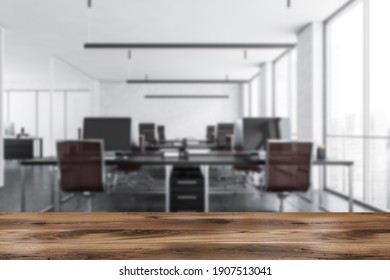 Wooden Desk Foreground And Blurred Background Office Room With Armchairs And Computers On The Tables Near Windows. 3D Rendering No People