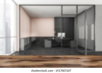 Wooden Desk Foreground On Background Of Blurred Office Room With Private Consulting Manager Room Behind Doors, Front View, Black Floor. 3D Rendering No People Mock Up To Display Product