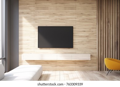 Wooden Living Room Interior With A TV Set Hanging On The Wall And A Narrow Sofa Near A Panoramic Window. 3d Rendering Mock Up