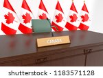 Wooden table with desk plate CANADA and Canadian flags behind. 3D Illustration.