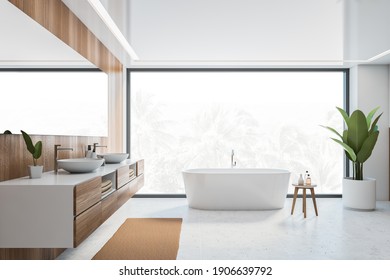 Wooden and white bathroom with bathtub, front view, large window with palms outdoors. Minimalist modern bathroom with sinks and mirror on white tiled floor 3D rendering, no people