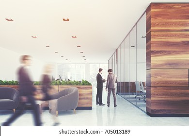 Wooden And White Company Office With Plants, A Glass Wall Conference Room And A Waiting Area With Blue Armchairs And A Coffee Table. People. 3d Rendering Toned Image