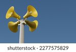 Yellow public address notification megaphones on a post against blue sky, 3d rendering. Outdoor notification loudspeakers for announcement or air raid alert