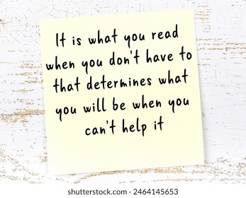 Yellow sticky note with smart quotation handwritten on it hanging on wooden wall