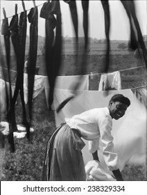 A young African American woman working in the midst of clotheslines heavy with sheets and stockings, photograph by Gertrude Kasebier, 1902.
