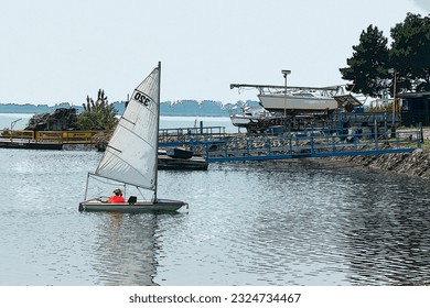 A young woman is sailing on a sailboat with the wind in the sails in the harbor - Powered by Shutterstock