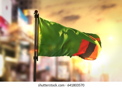 Zambia Flag Against City Blurred Background At Sunrise Backlight 3D Rendering